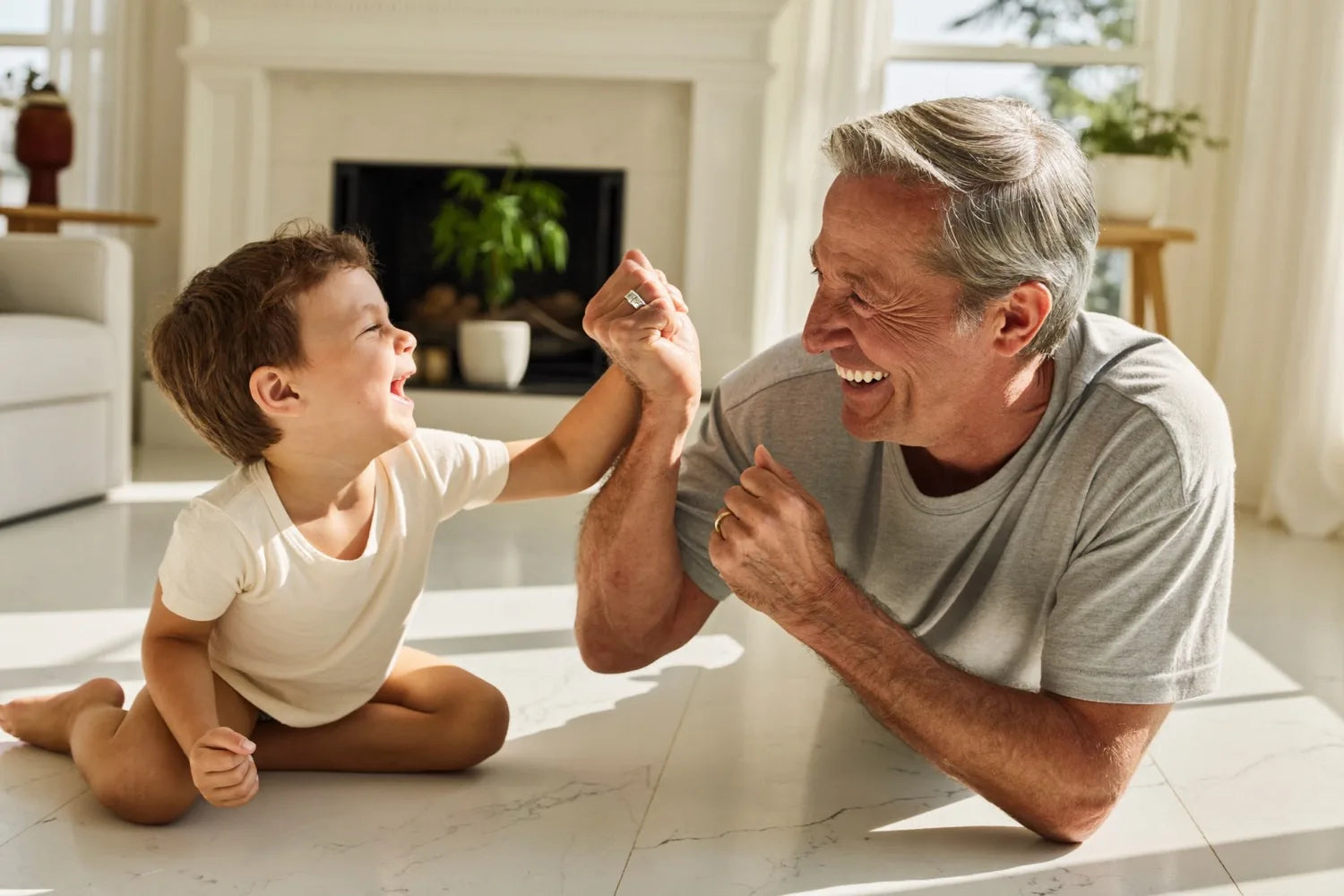 A grandparent down on the floor playing with a laughing grandchild
