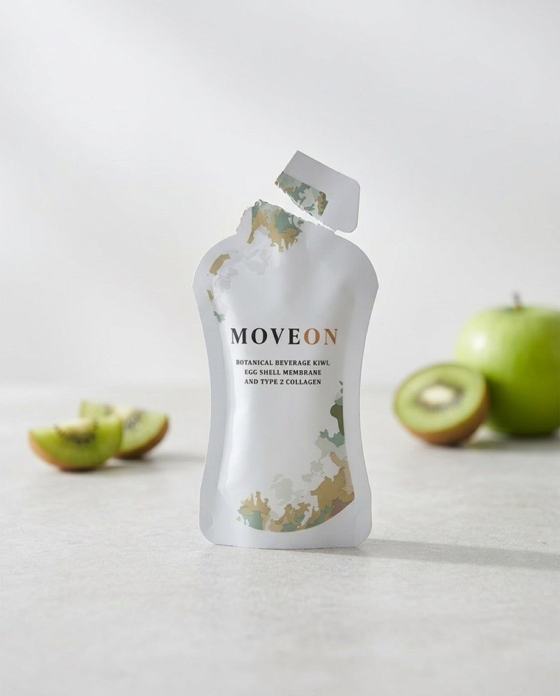 A MoveOn sachet on a sunlit counter beside a glass of its amber-orange juice
